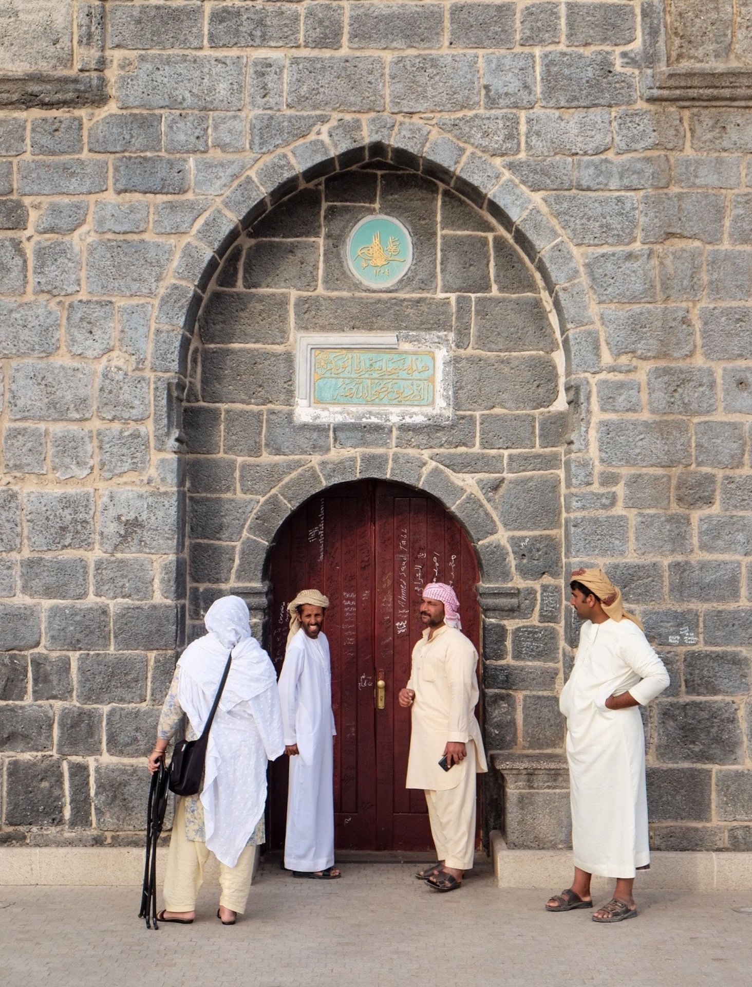 Local guide speaking with pilgrims at a historic stone archway in Madinah